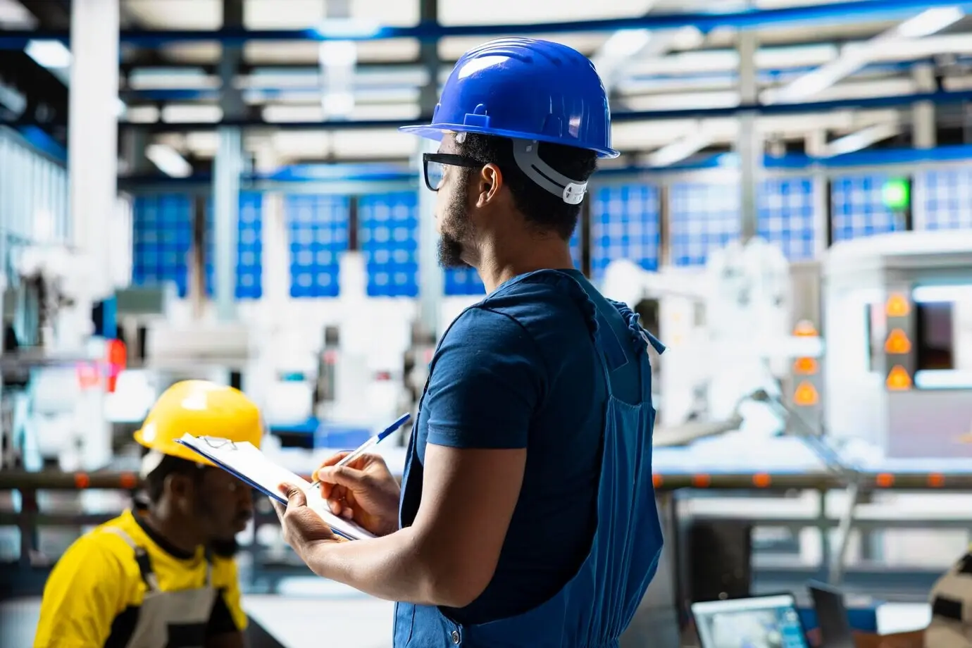 Eine afroamerikanische Aufsichtsperson bewertet Kennzahlen zu erneuerbaren Energien in einer Fabrik.